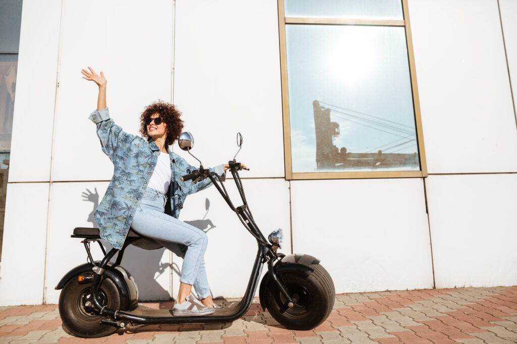 Happy smiling woman sitting on a modern motorbike